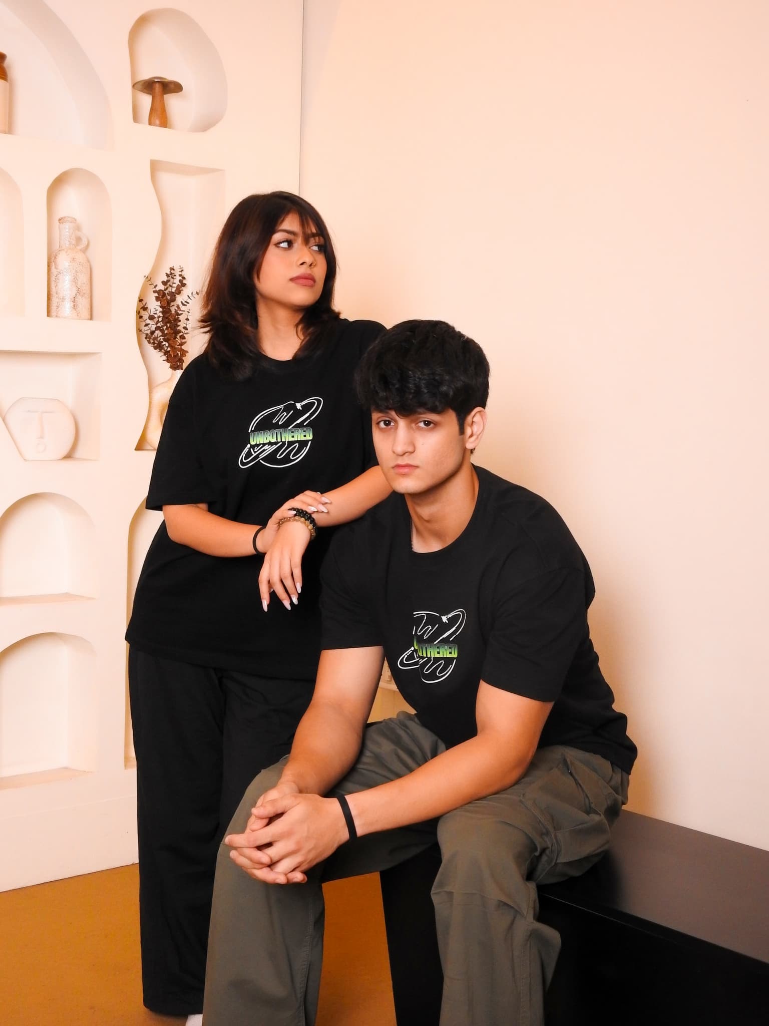 Male and female models seated in Unbothered tees